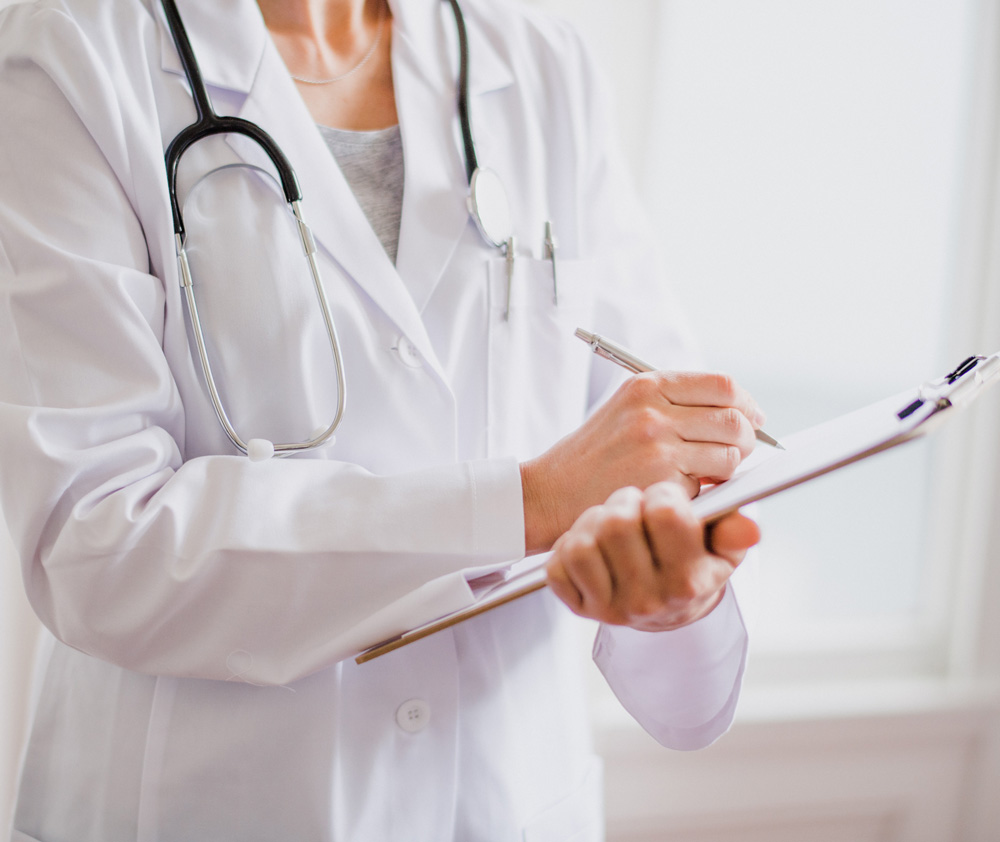 Doctor with stethoscope in white coat holding clipboard, writing medical record diagnosis, isolated on white background, close up, cropped view.