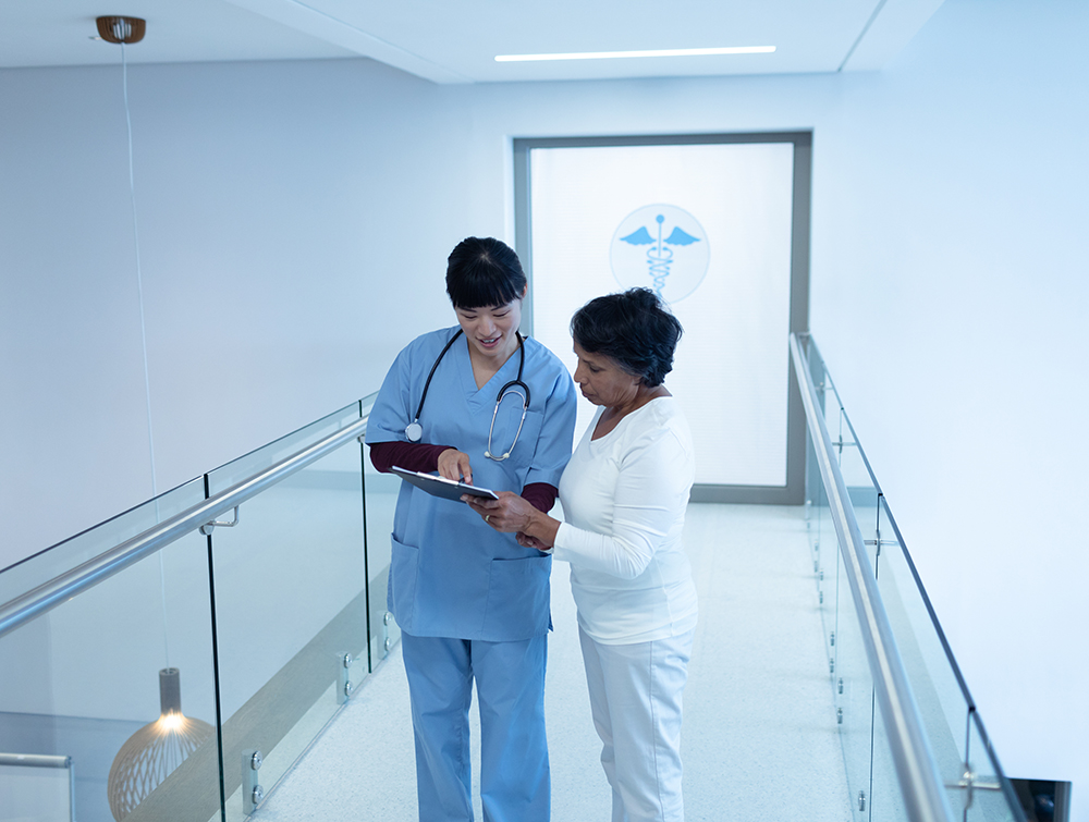 Female doctor discussing over clipboard with female patient in the corridor