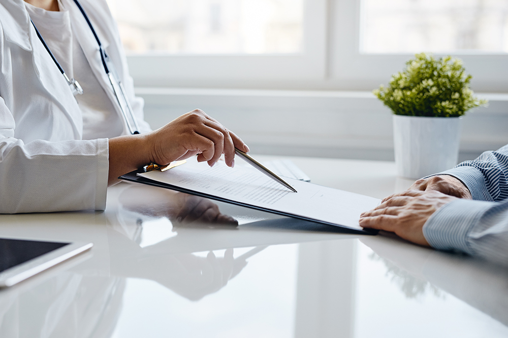 Female doctor recommends to fill in a medical document in the office.