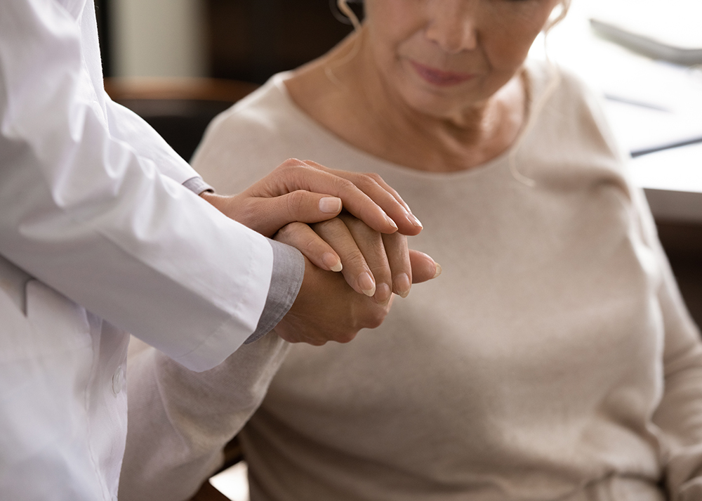 Disabled senior female hand in palms of young woman medic