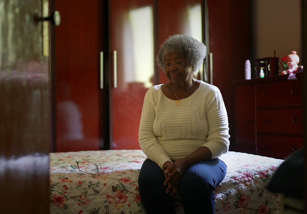 One senior black woman sitting by bedside in bedroom