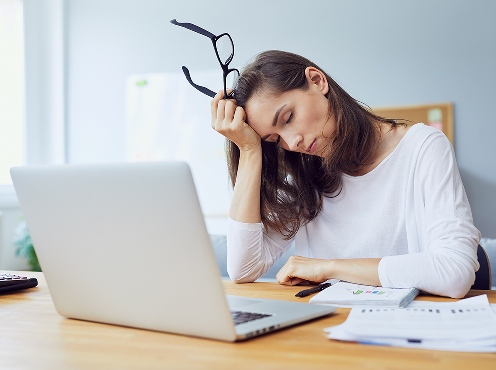 Gorgeous tired young office worker falling asleep at her desk while trying to work in modern office